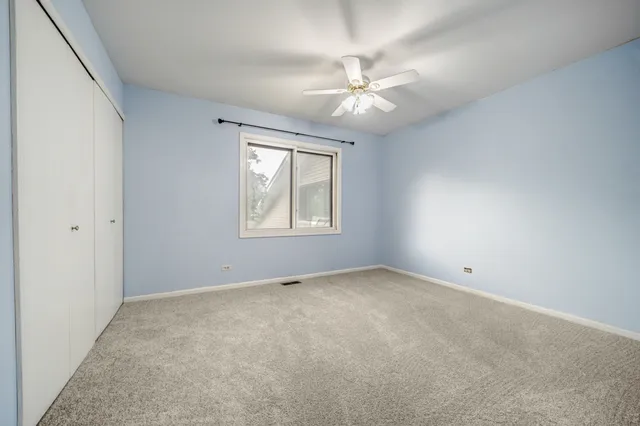 an empty room with windows and ceiling fan