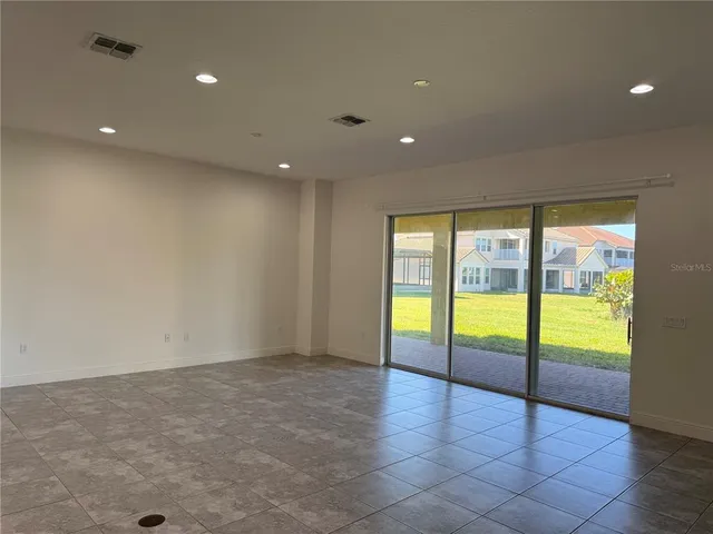 a view of an empty room with glass door and wooden floor