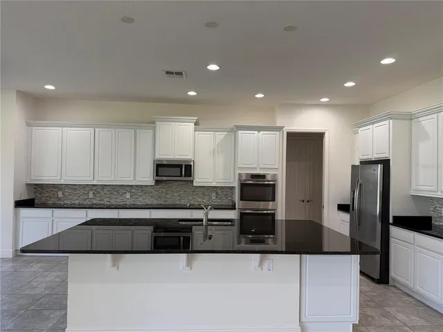 a large kitchen with kitchen island granite countertop a stove a sink a microwave and a refrigerator