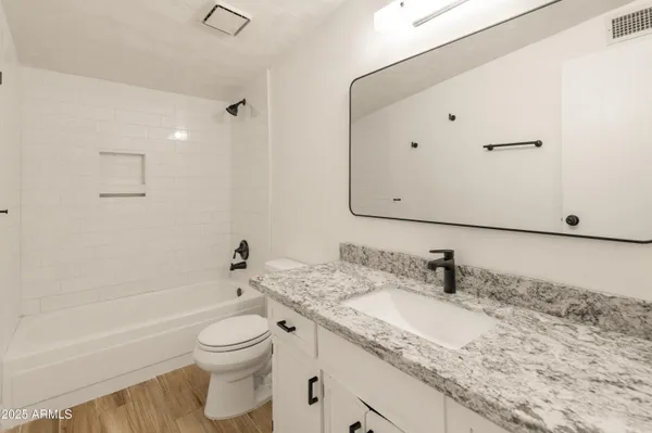 a bathroom with a granite countertop sink a toilet and a bathtub