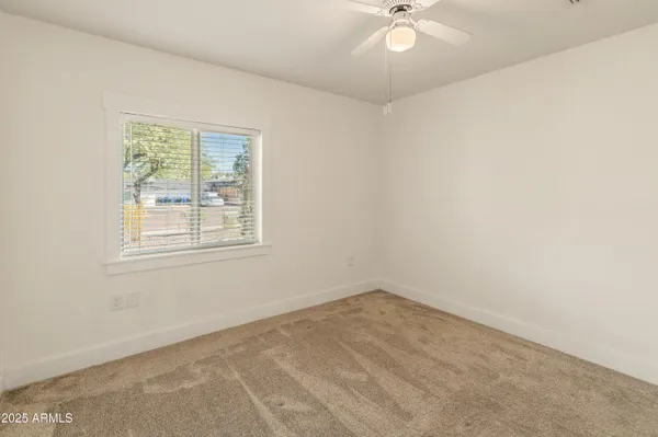 an empty room with a window and a ceiling fan