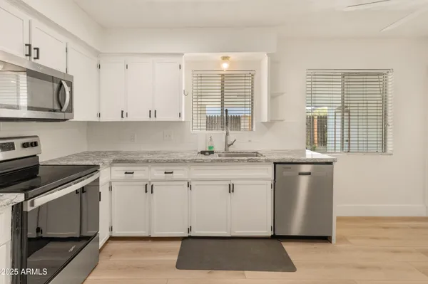 a kitchen with granite countertop white cabinets and white appliances