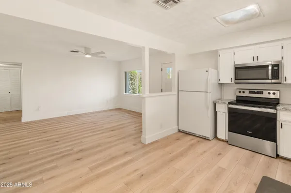 a view of a kitchen with wooden floor electronic appliances and windows