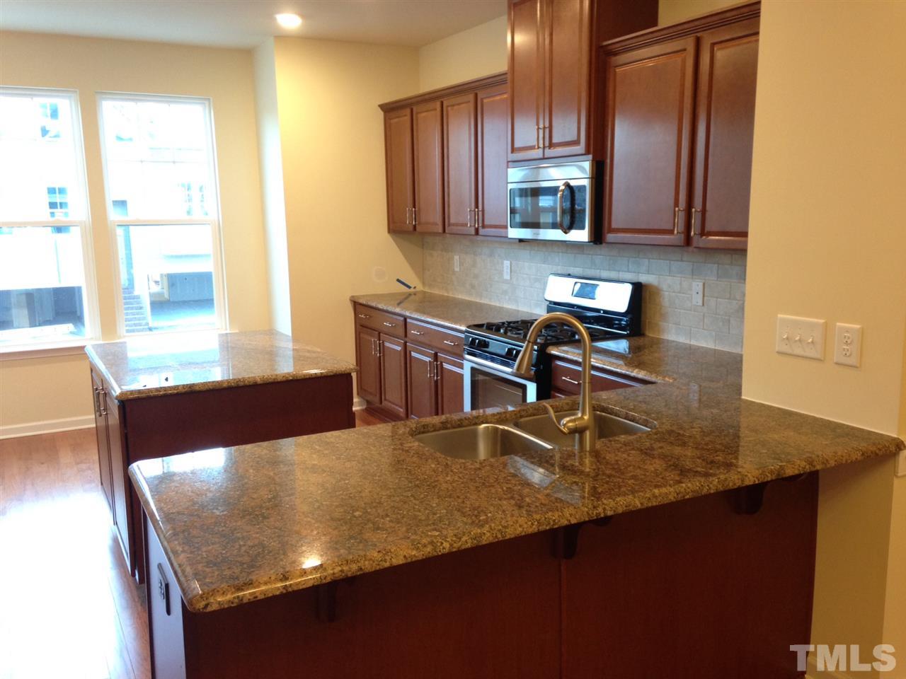 604 Edgewater Ridge Court Apex, NC 27523 - Photo 4 of 20 a kitchen with stainless steel appliances granite countertop a sink a stove and a microwave