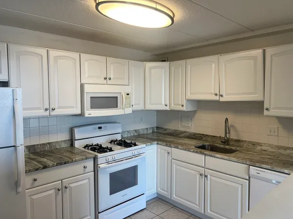 a kitchen with granite countertop white cabinets and white appliances