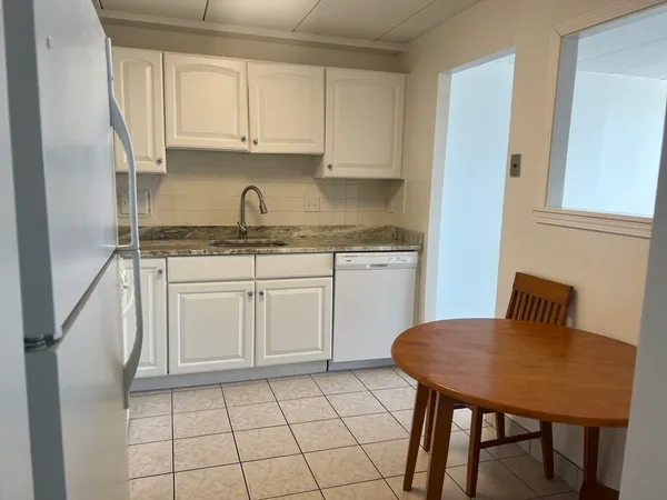 a kitchen with granite countertop a sink white cabinets and white appliances