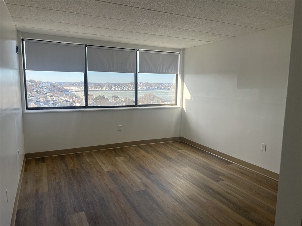 1 Pond Street, Unit 10M Winthrop, MA 02152 - Photo 8 of 12 an empty room with wooden floor and windows