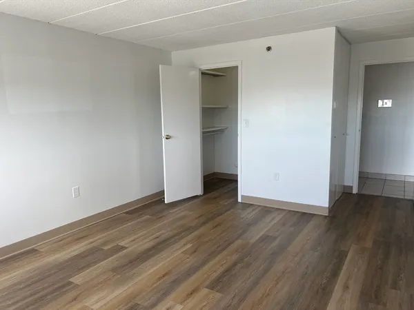a view of an empty room with wooden floor and closet