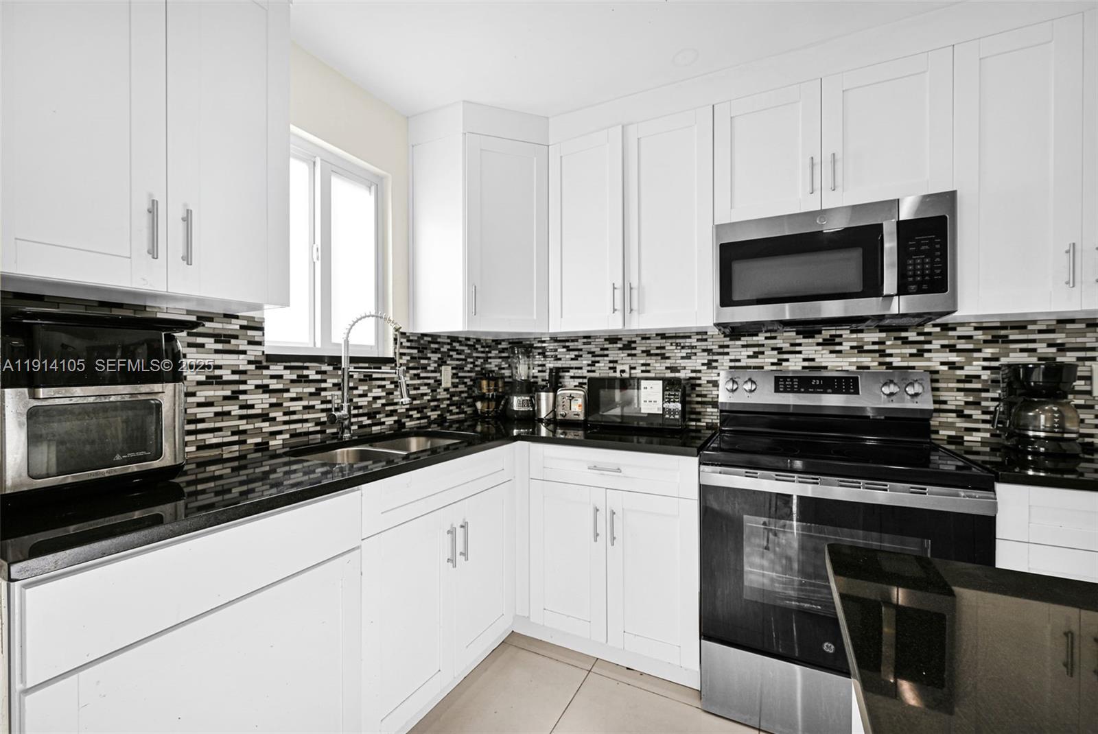 26100 Southwest 134th Place Homestead, FL 33032 - Photo 10 of 39 a kitchen with granite countertop a sink stove and microwave