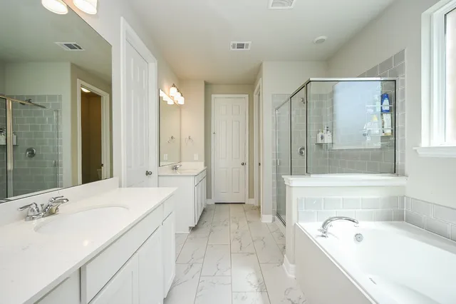 a spacious bathroom with a tub sink shower and mirror