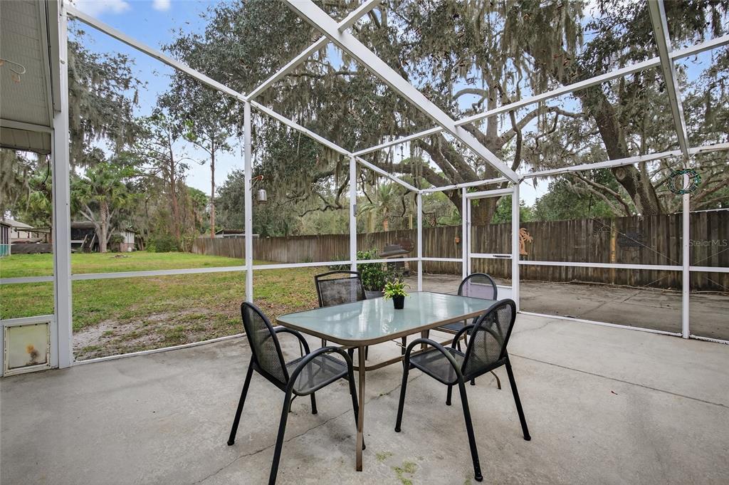 2218 River Ridge Road DeLand, FL 32720 - Photo 15 of 52 a view of a backyard with table and chairs and wooden fence