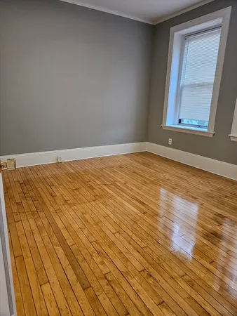 a view of an empty room and wooden floor and a window