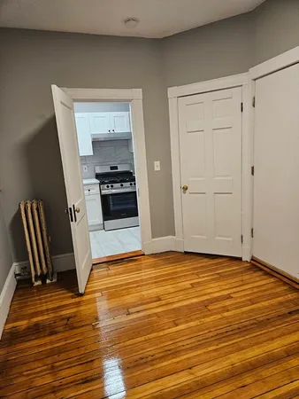 a view of kitchen and empty room with wooden floor