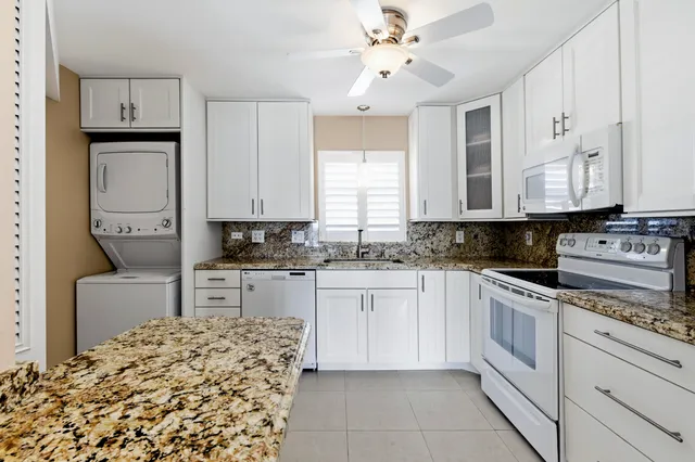 a kitchen with granite countertop a sink stainless steel appliances and window