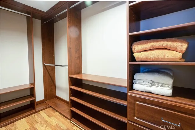 an empty room with wooden floor cabinet and windows