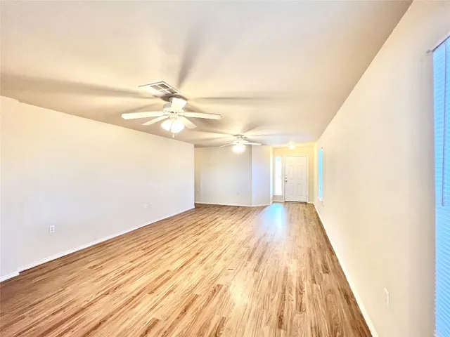 a view of a room with wooden floor and a ceiling fan