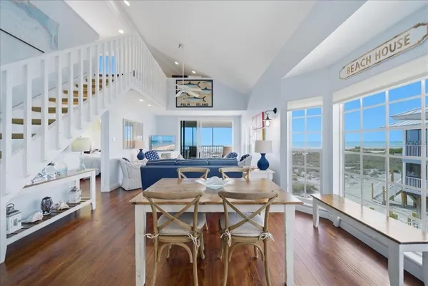 a living room with furniture a large window and wooden floor