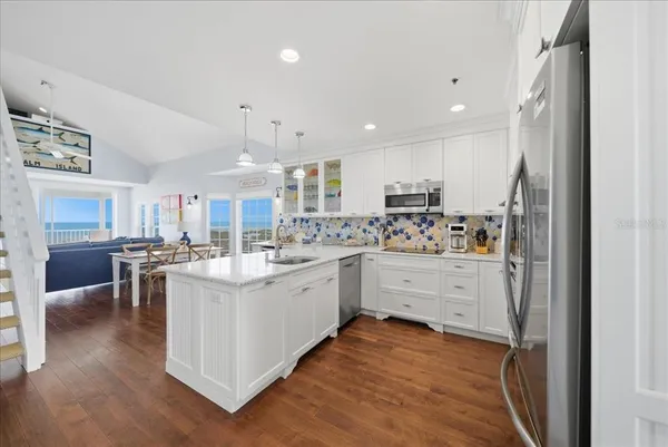 a kitchen with a sink stainless steel appliances and wooden floor