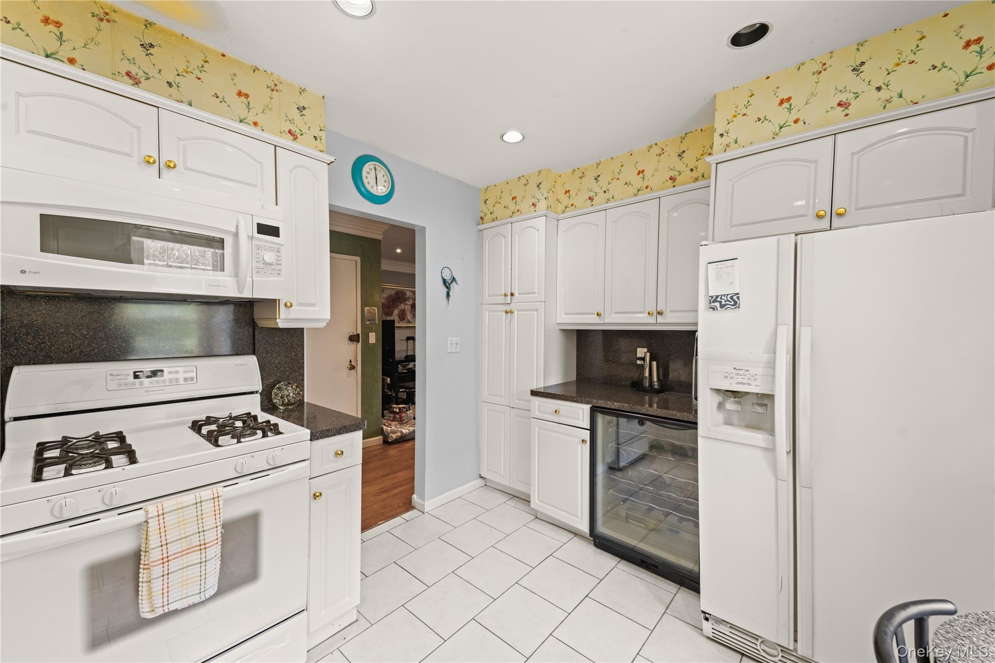 12-35 Robin Lane, Unit UPPR Queens, NY 11360 - Photo 15 of 23 Kitchen featuring white appliances, white cabinets, beverage cooler, light tile patterned floors, and wallpapered walls
