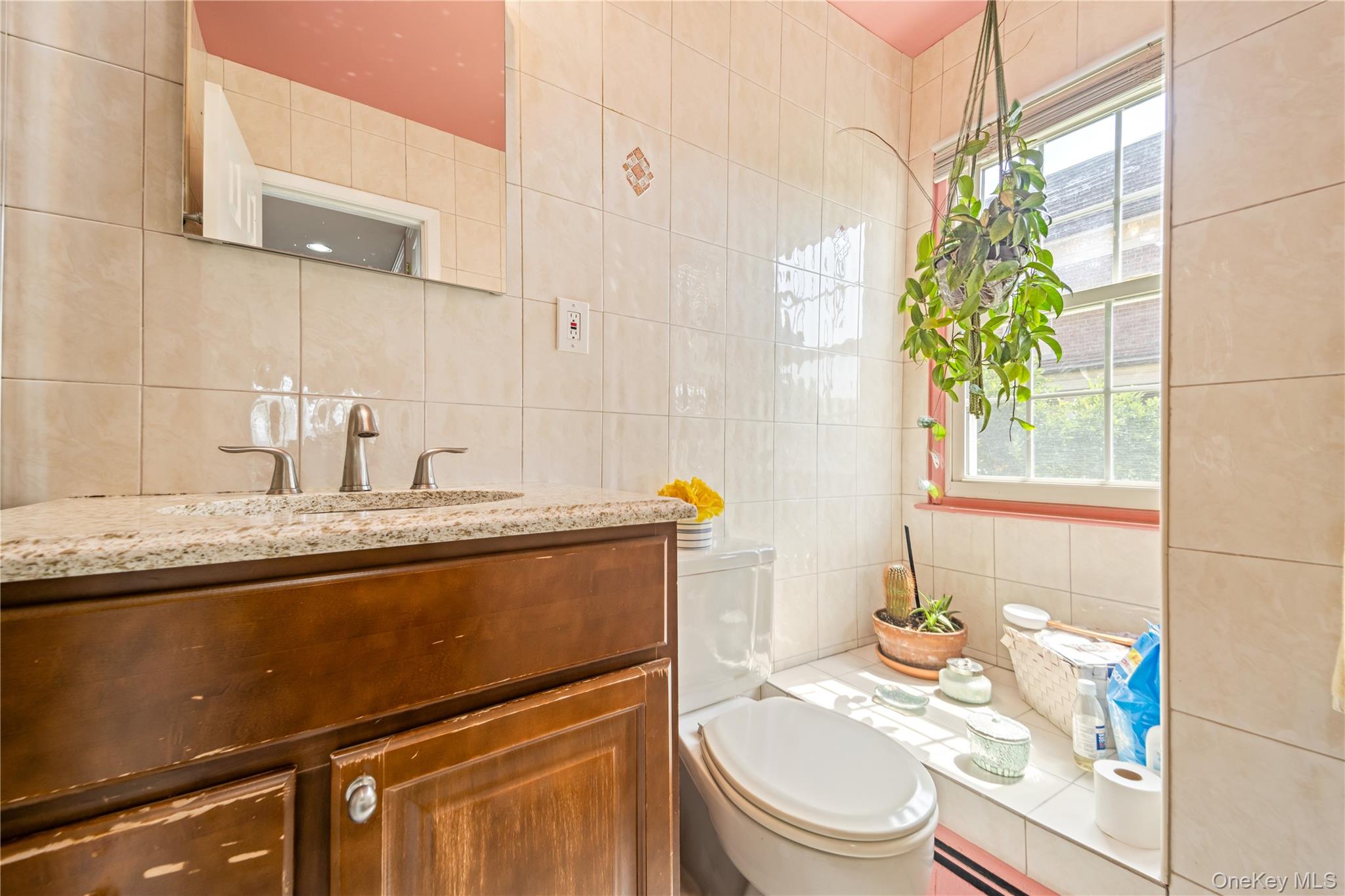 12-35 Robin Lane, Unit UPPR Queens, NY 11360 - Photo 21 of 23 Half bathroom with tile walls, vanity, decorative backsplash, and a baseboard radiator