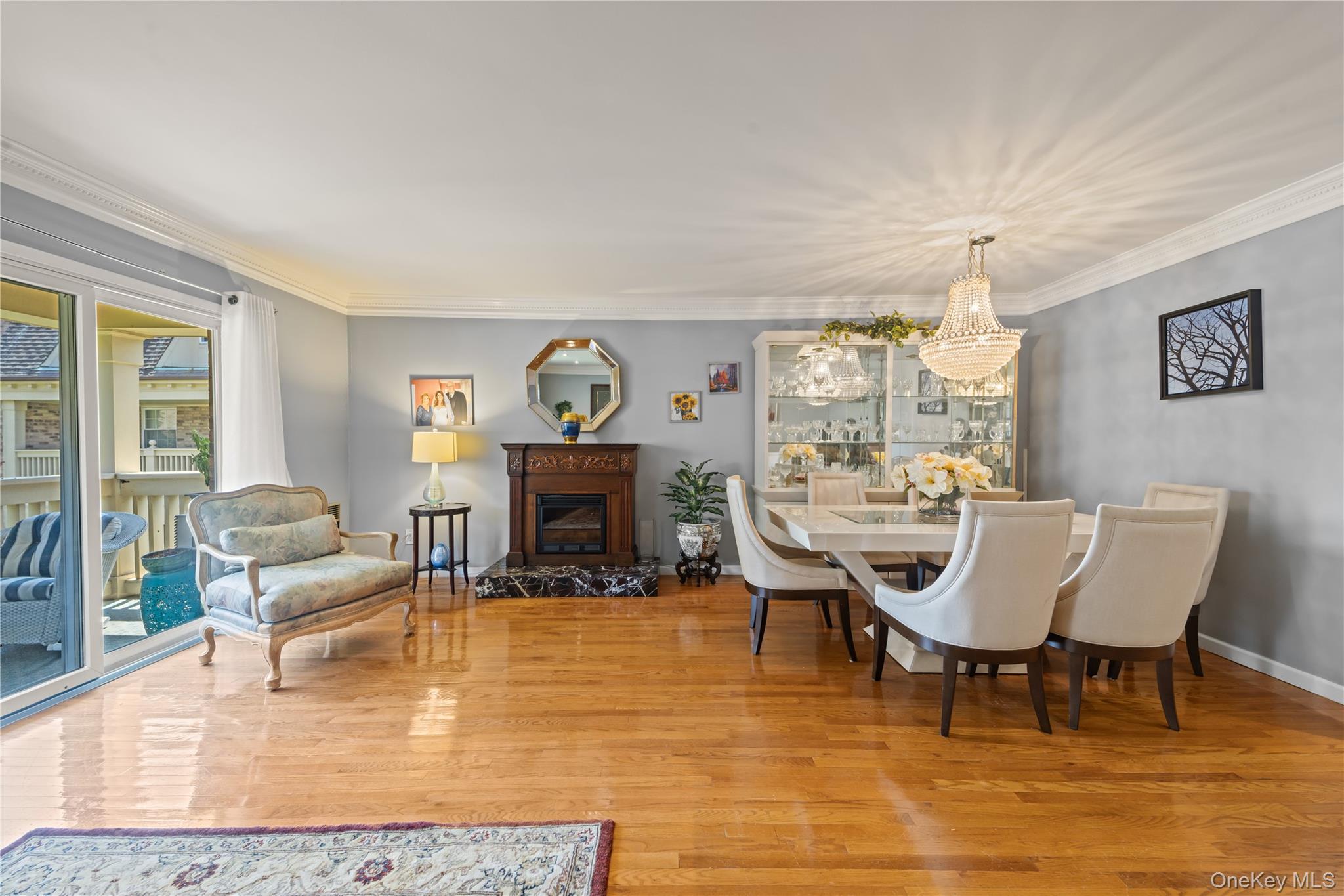 12-35 Robin Lane, Unit UPPR Queens, NY 11360 - Photo 5 of 23 Dining space featuring crown molding, light wood-type flooring, a glass covered fireplace, and a chandelier