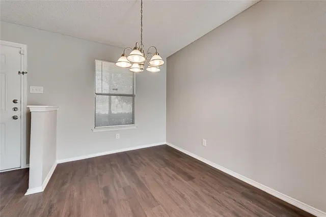 a view of a room with wooden floor chandelier and a window
