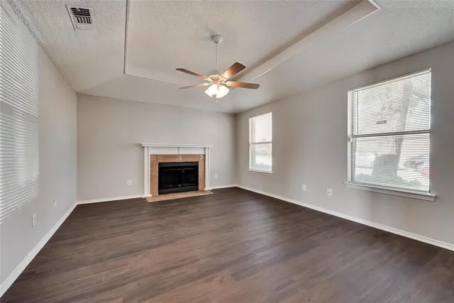 an empty room with chandelier fan and windows