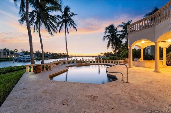 a view of a swimming pool with a lounge chair and palm trees