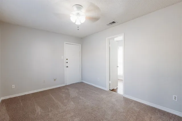 an empty room with a chandelier fan and windows
