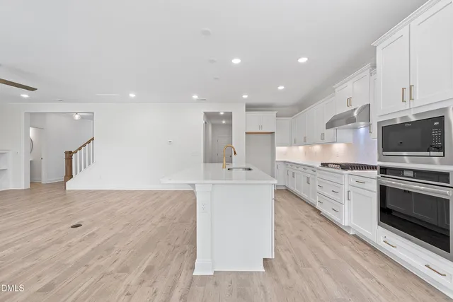 a large kitchen with stainless steel appliances kitchen island a large counter top and a stove top oven