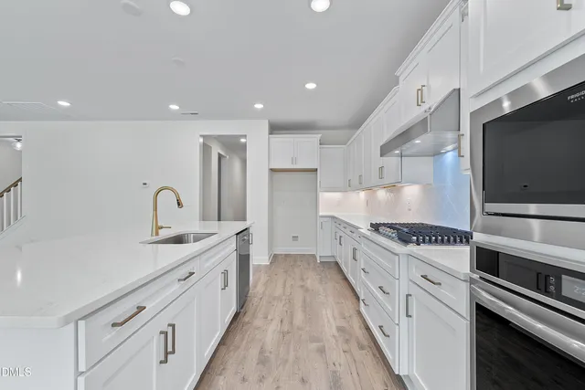 a large kitchen with stainless steel appliances granite countertop a lot of counter space and wooden floors