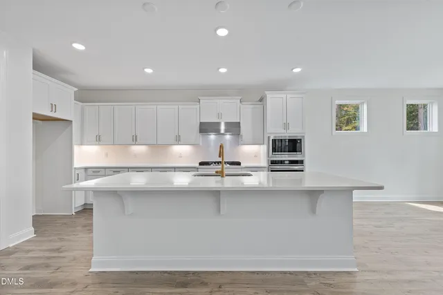 a kitchen with kitchen island sink stove and cabinets