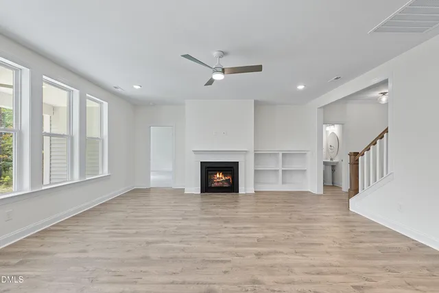 a view of a livingroom with a fireplace a ceiling fan and windows