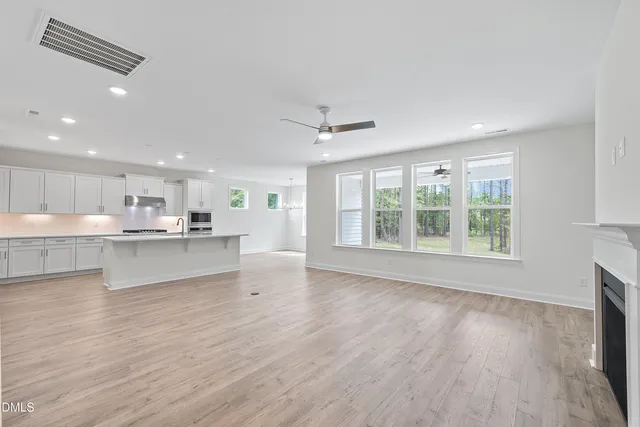 a view of a livingroom with a fireplace a ceiling fan and windows