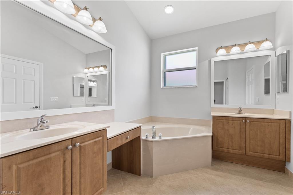 9300 Springview Loop Estero, FL 33928 - Photo 20 of 50 a bathroom with a bathtub a double vanity sink and mirror