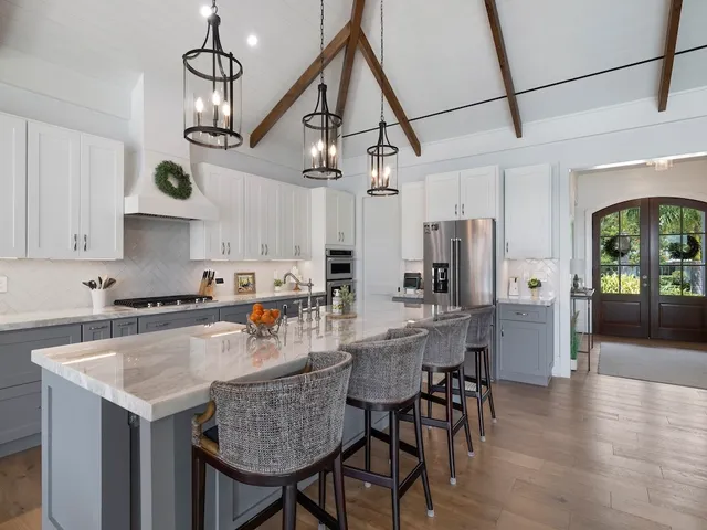 a kitchen with stainless steel appliances granite countertop a stove a refrigerator a kitchen island a dining table and chairs with wooden floor