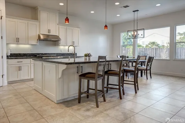 a kitchen with granite countertop a table chairs sink and cabinets