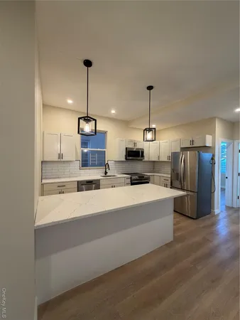 a large kitchen with stainless steel appliances kitchen island a stove a sink a center island and a wooden floor