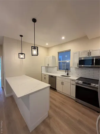 a large kitchen with stainless steel appliances kitchen island a stove a sink a center island and a wooden floor