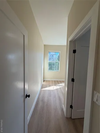 a view of an empty room with window and wooden floor