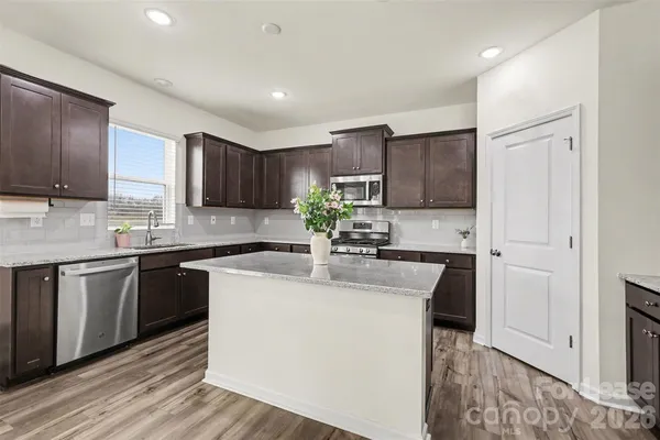 a kitchen with kitchen island granite countertop wooden cabinets and white appliances
