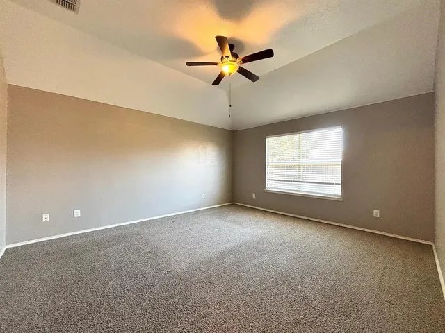 an empty room with windows and ceiling fan