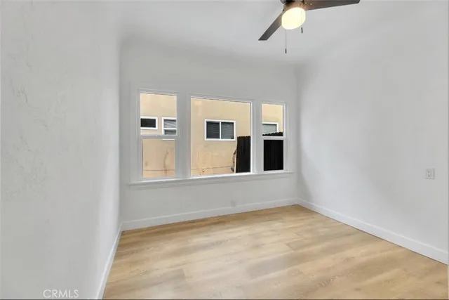 an empty room with windows and ceiling fan