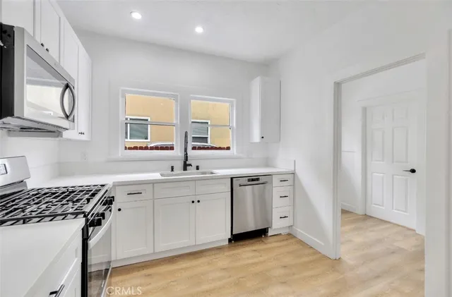 a kitchen with stainless steel appliances a sink stove and cabinets