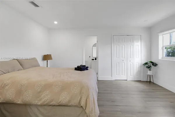 a spacious bedroom with a bed and wooden floor