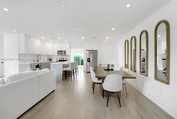 a living room with stainless steel appliances furniture a rug kitchen view and a kitchen island