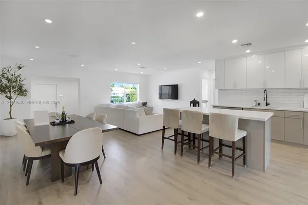 a living room with couches chairs and kitchen view with wooden floor