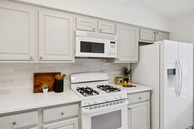 a white kitchen with stove and white cabinets