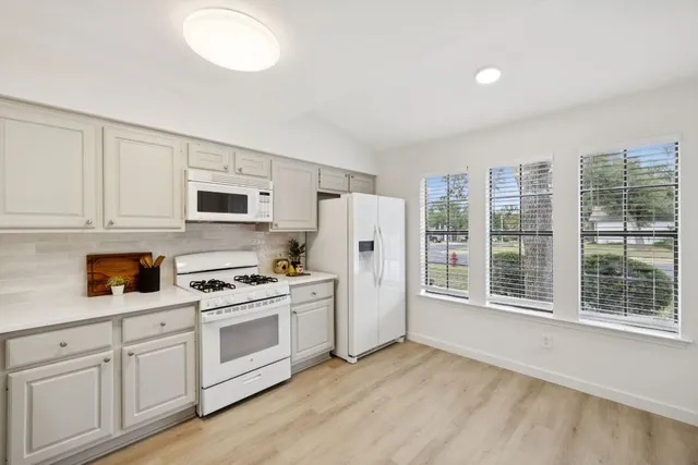 a kitchen with white cabinets and wooden floor