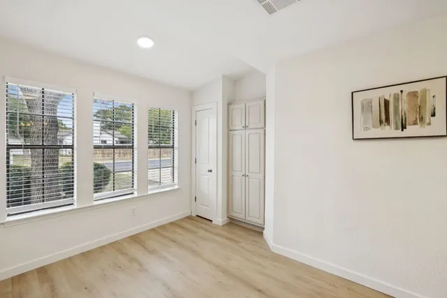 a view of an empty room with a window and wooden floor